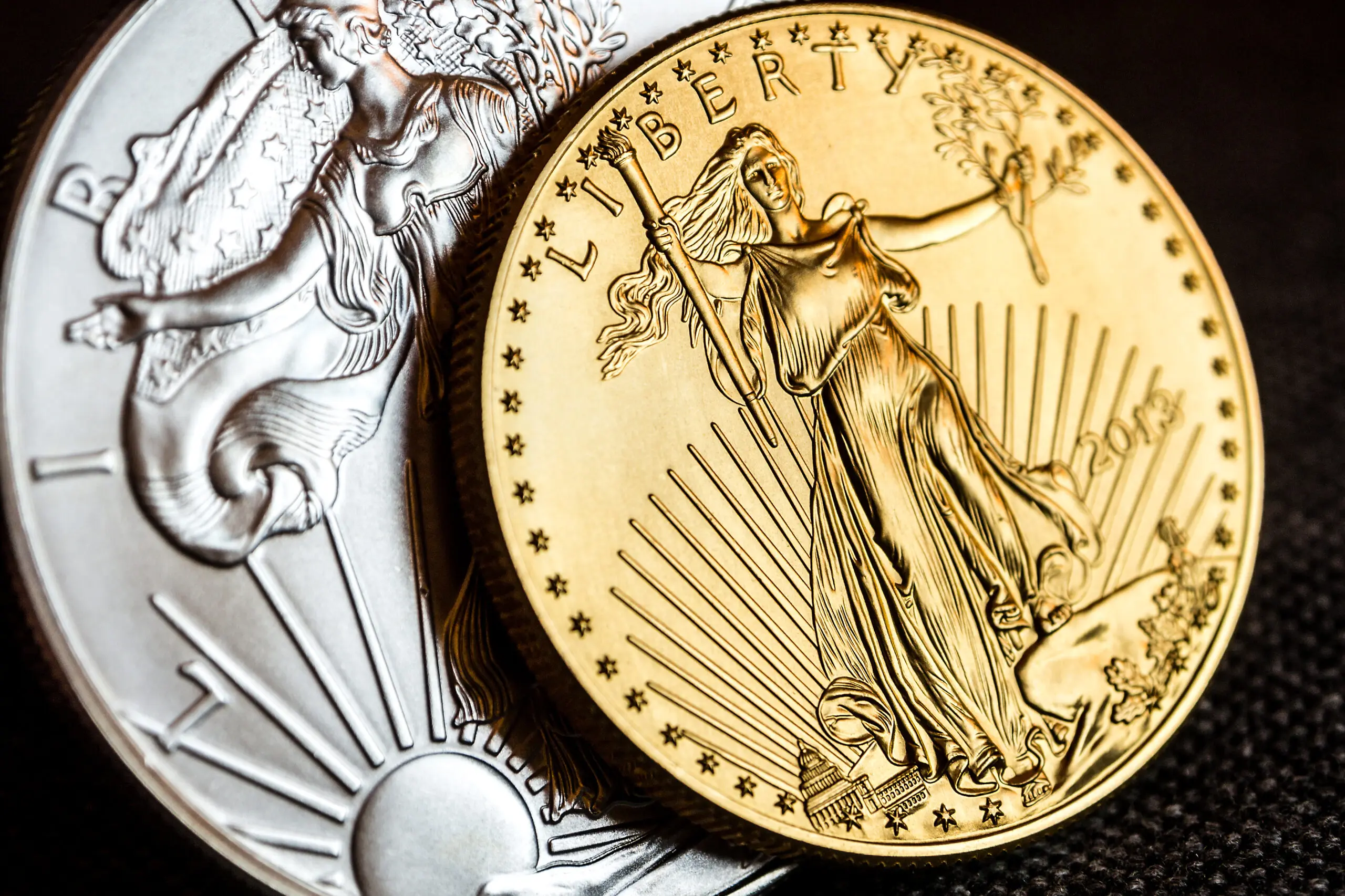 silver eagle and golden american eagle one ounce coins closeup of silver eagle and golden american eagle one ounce coins on black background