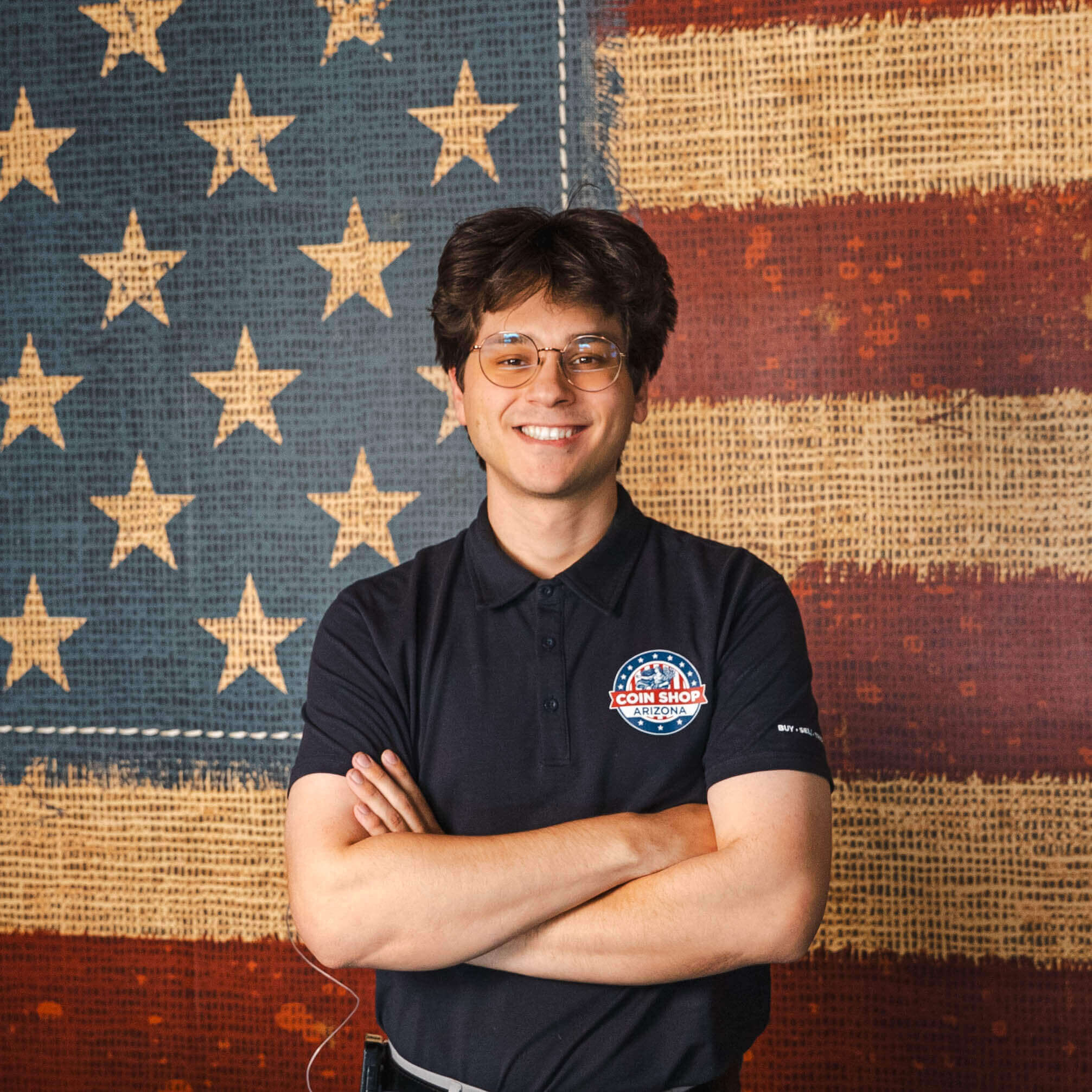 Person smiling in front of American flag.