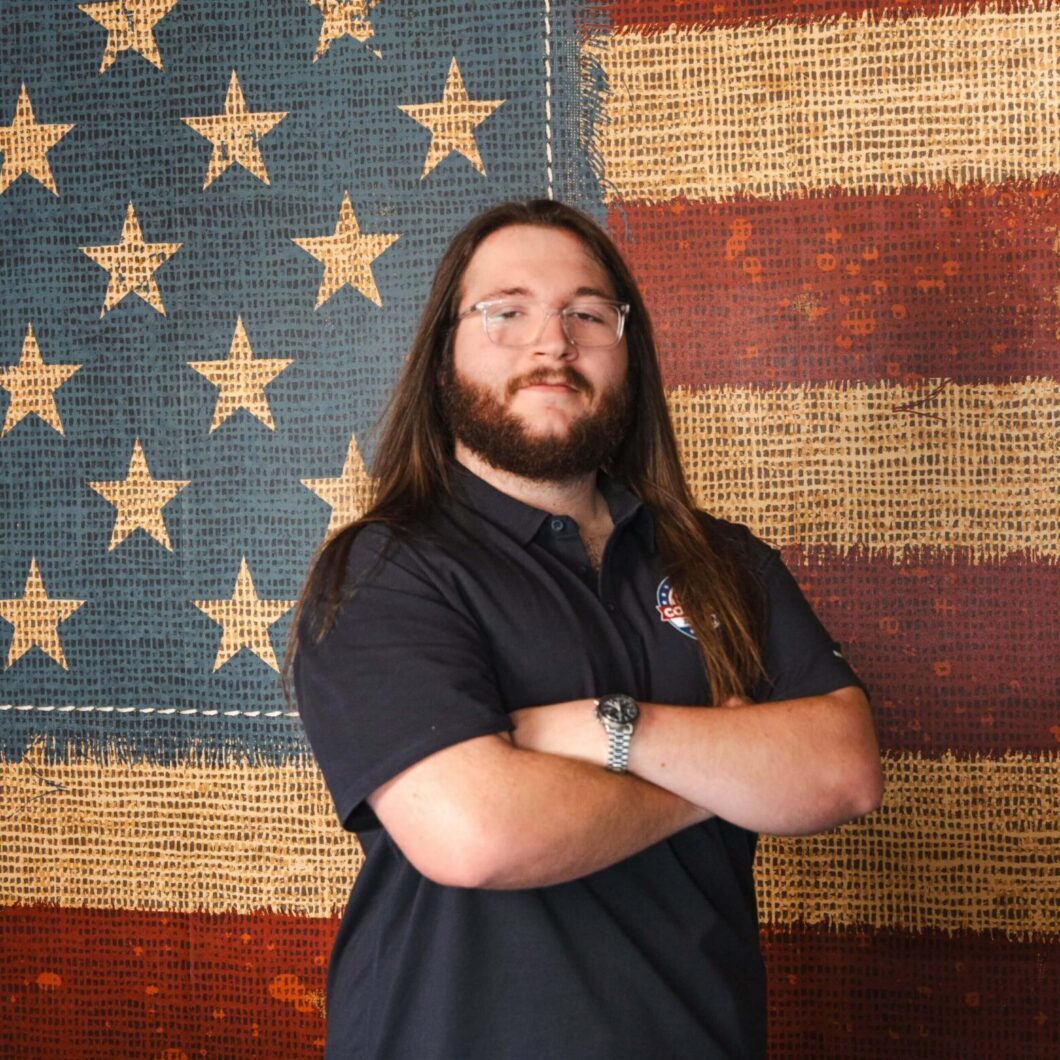 Bearded man with glasses before vintage flag