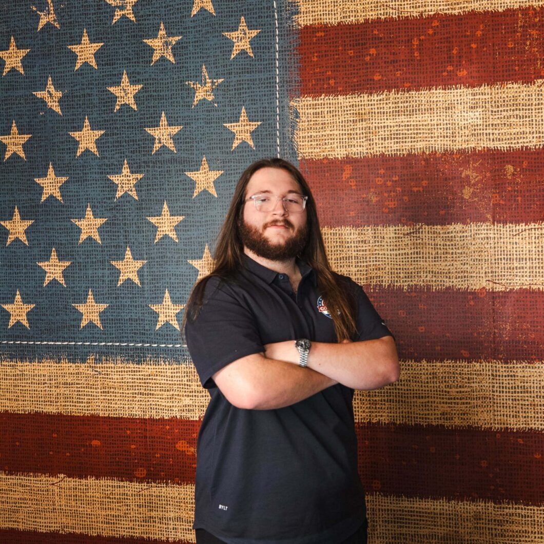 Long-haired employee standing by textured flag